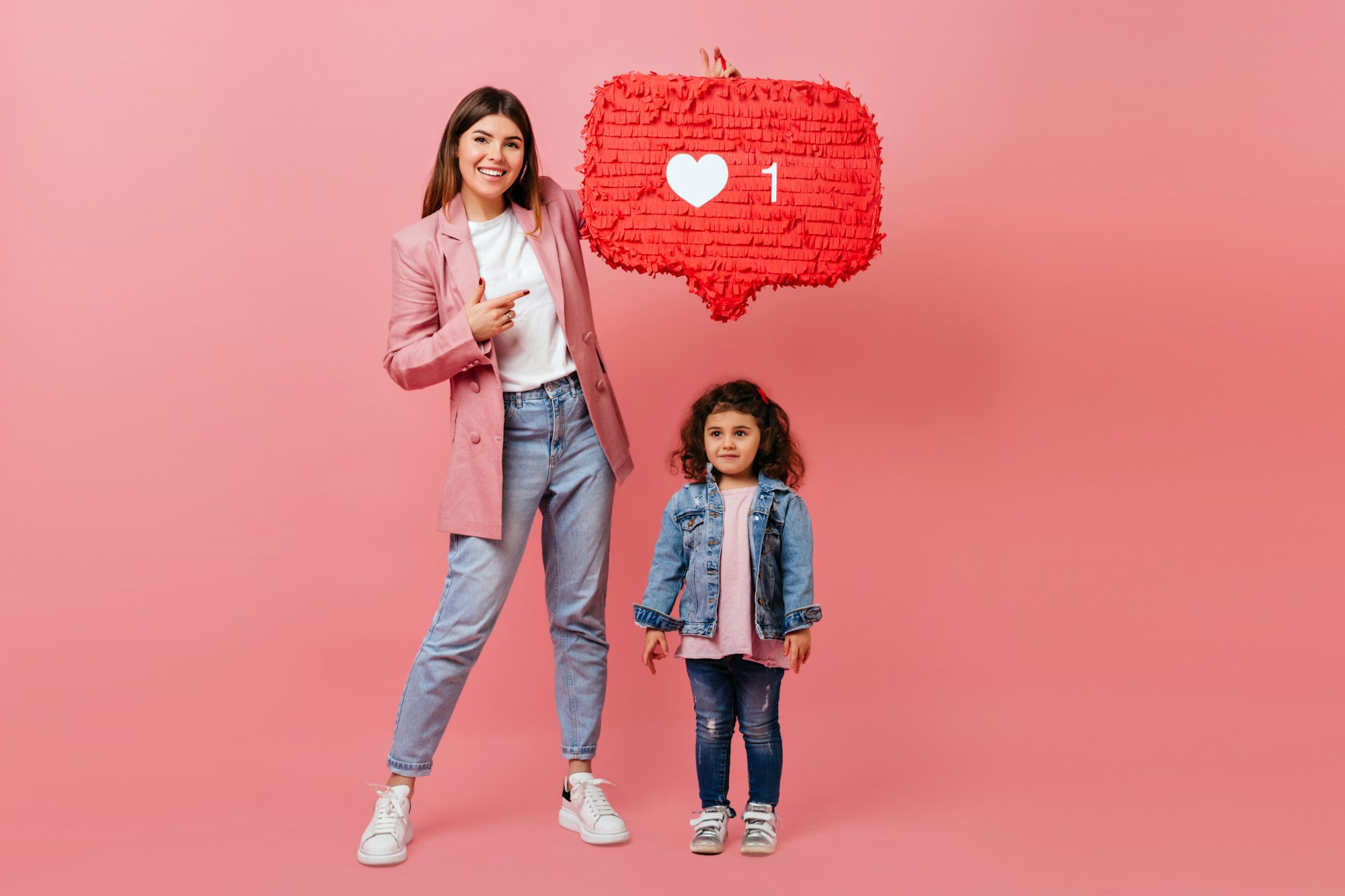 Full length view of trendy mom and daughter posing with like icon. Studio shot of family with socia